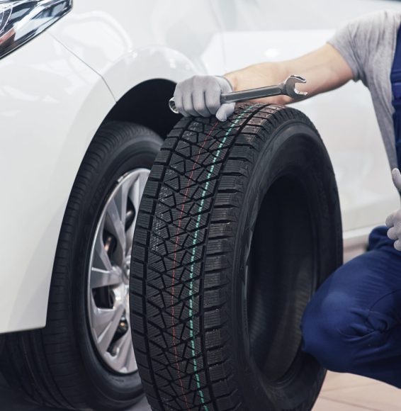Technician with a blue workwear, holding a wrench and a tire while showing thumb up Technician with a blue workwear, holding a wrench and a tire while showing thumb up.